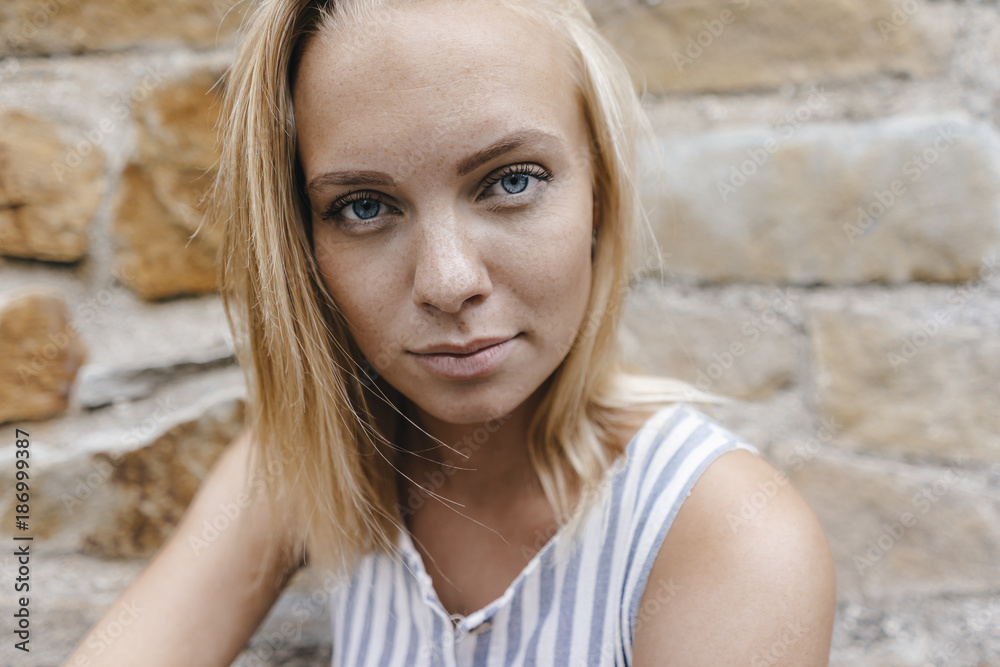 Portrait of young woman at natural stone wall