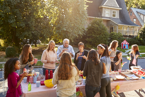 Neighbours talk and eat around a table at a block party