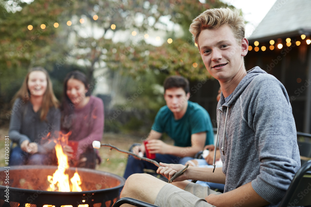 Fototapeta premium Teenage boy with friends toasting marshmallow at a fire pit