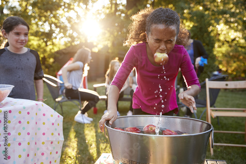 Pre-teen girl, apple in mouth, apple bobbing at garden party photo