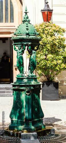 Typical Parisian drinking fountain with cast-iron women group at city square. Paris, France