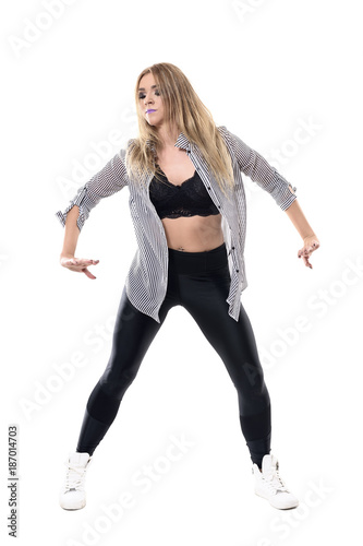 Dancing motion of young attractive blonde woman jazz dancer with unbuttoned striped shirt. Full body length portrait isolated on white background. 