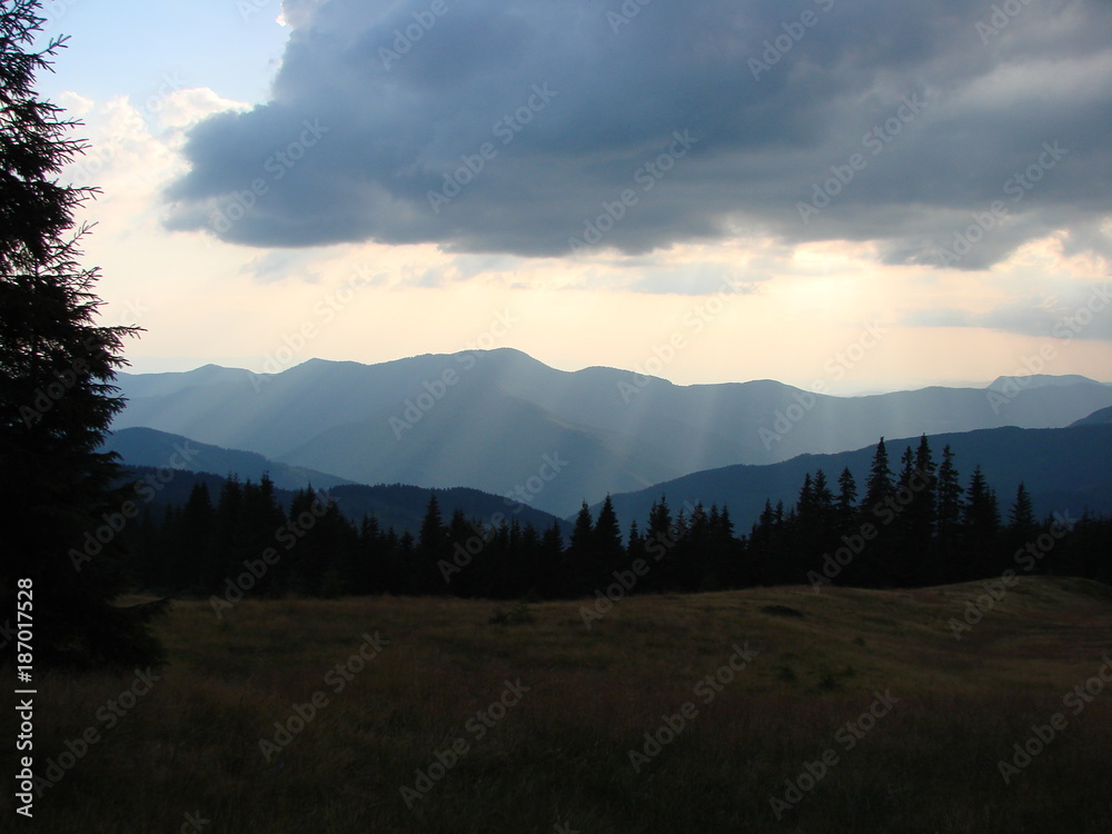 The landscape of the mountain ranges of the Ukrainian Carpathians on the background of the cloudy sky at sunset.
