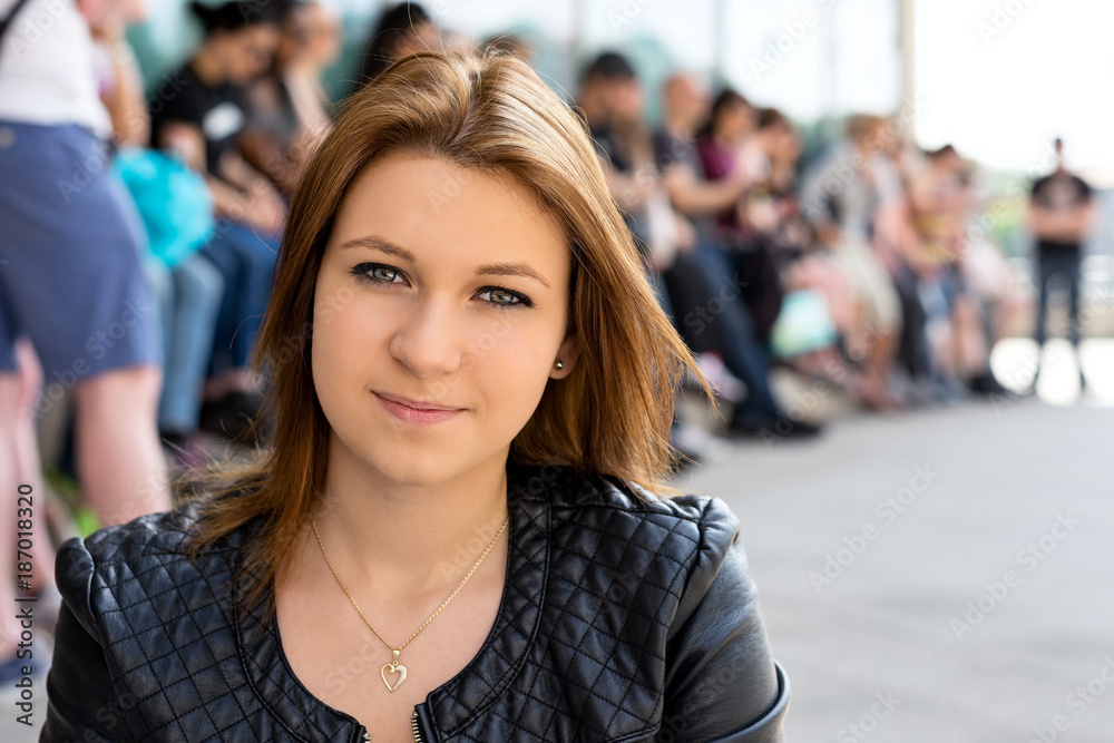 Bright close-up portrait of an attractive university student girl with her classmates in the background. She is a team leader!