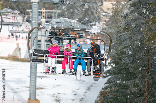 Parents with children climb up on the ski terrain with chair lift