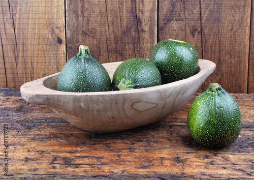 round zucchini in a wooden bowl on plank 