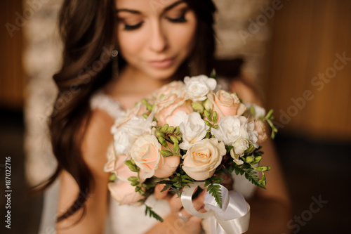 cute bride holding wedding bouquet of white and peach roses