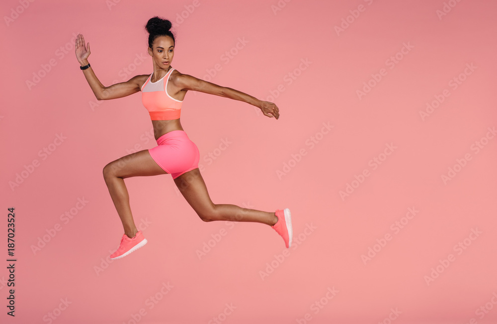 Healthy african woman sprinting on pink background