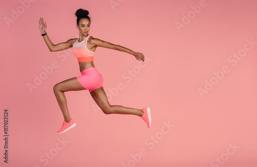 Healthy african woman sprinting on pink background