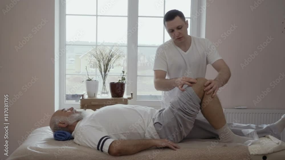 Professional masseur massages old man's knee in slowmotion Professional masseur massages old man's knee in slowmotion