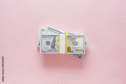 Overhead view of stack of 100 dollar bills on pink background