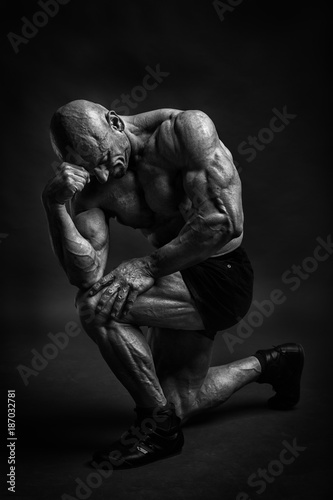Professijnal bodybuilder and fitnes model posing in studio like a philosopher. Black and white low kay version.