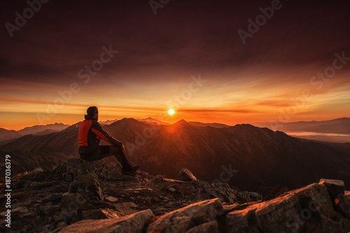 Man seating on the top of mountain at sunrise  hiking and climbing 