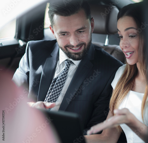 Smiling business people working in backseat of car