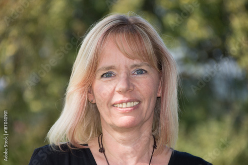 Porträt einer Blonde Frau im Sommer vor grünem Hintergrund