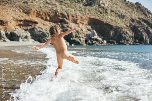 young naked toddler jumping into the ocean, crete, greece