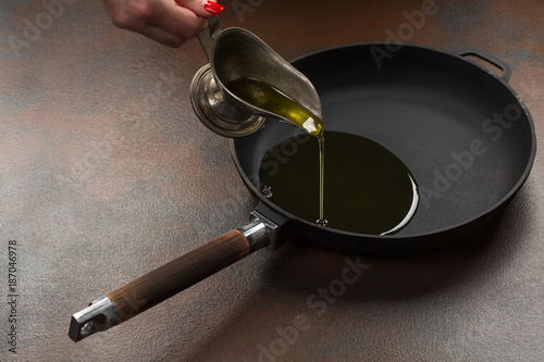 Olive oil poured into the frying pan from the sausage