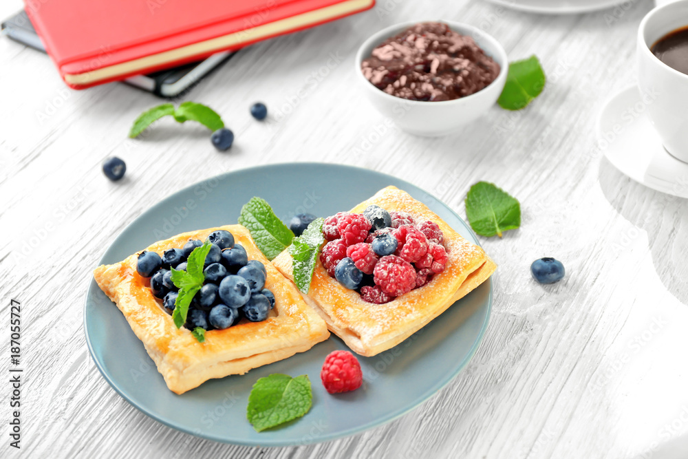 Plate with yummy berry puff pastry on wooden table