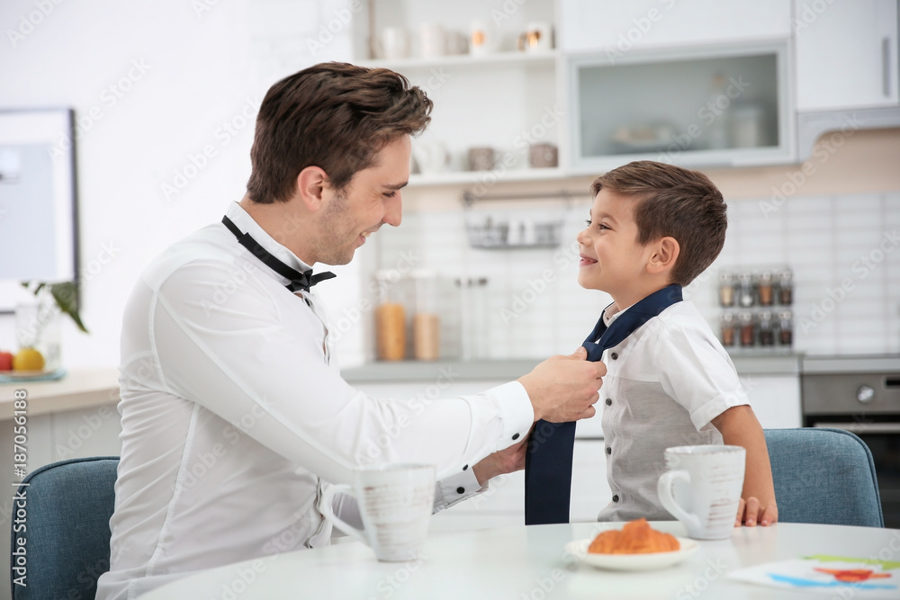 Young father helping his little son to knot necktie at home Young father helping his little son to knot necktie at home
