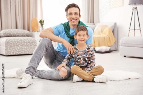 Portrait of father and son sitting on floor at home
