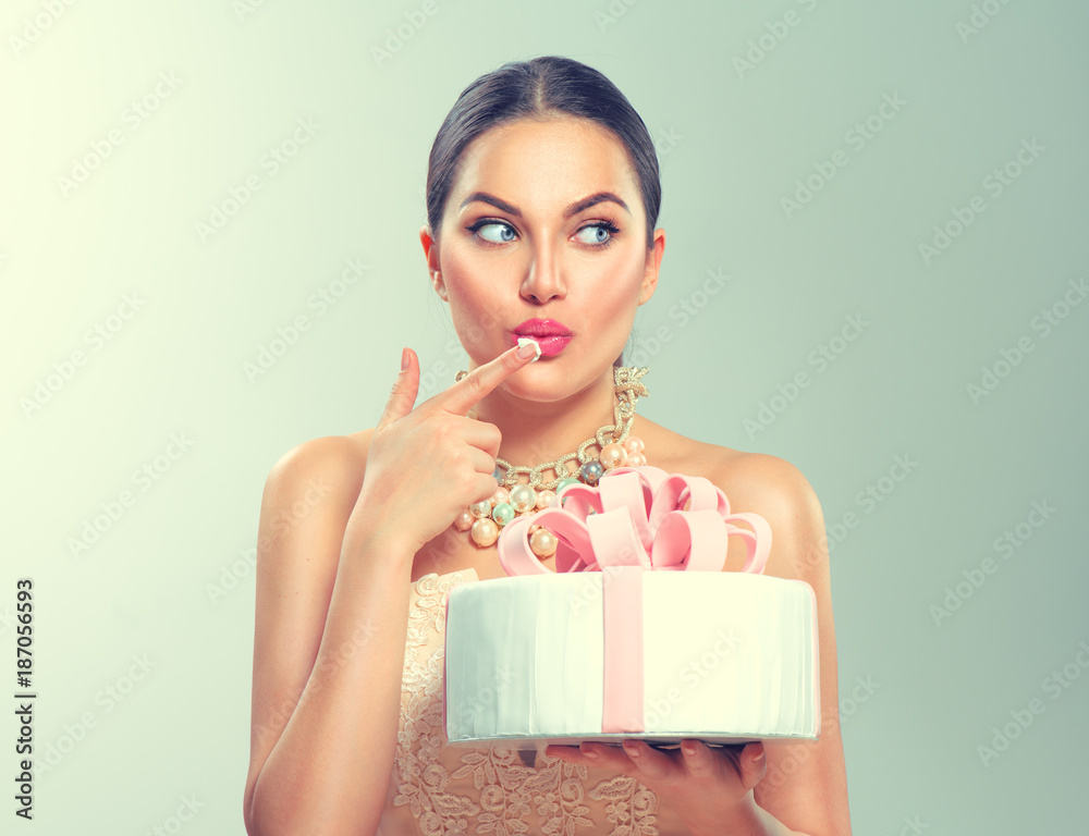 Funny joyful beauty model girl holding big beautiful party or birthday cake over green background Funny joyful beauty model girl holding big beautiful party or birthday cake over green background