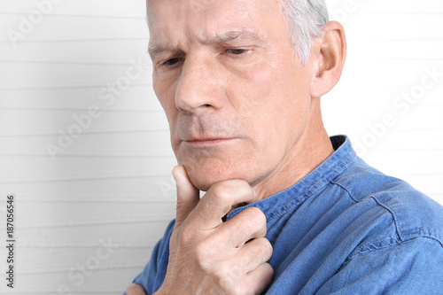 Charismatic thoughtful senior man on light background