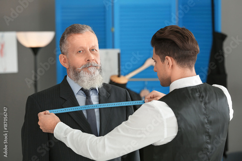 Tailor taking client's meas...
