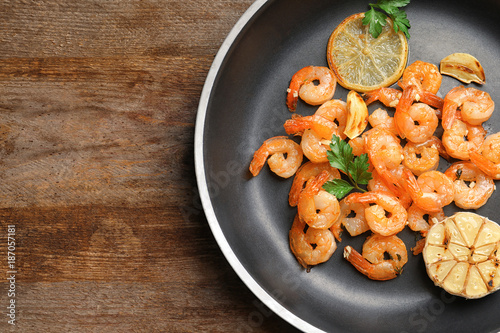 Frying pan with delicious shrimps and garlic on wooden table
