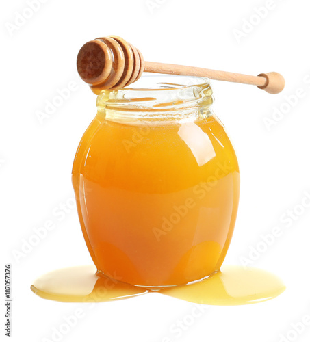 Glass jar with delicious honey and wooden dipper on white background