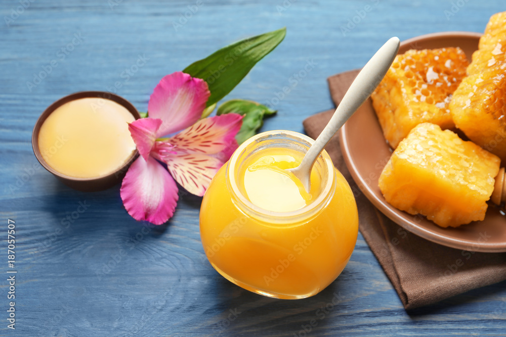 Glass jar with delicious honey on wooden background
