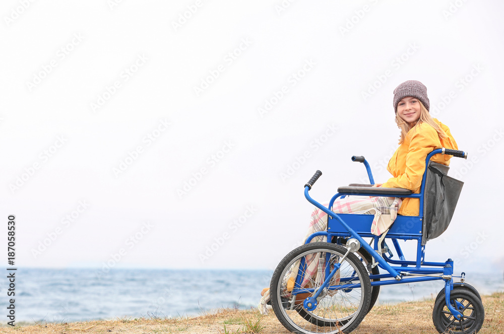 Cute girl in wheelchair on sea shore Cute girl in wheelchair on sea shore