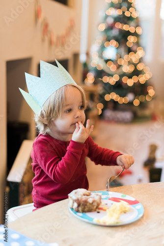 Toddler boy eating cake at home