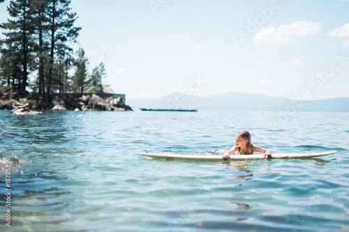 Young Girl Resting on Surfboard in Lake