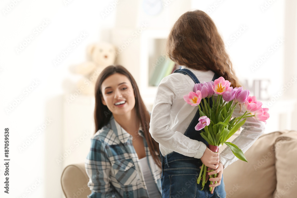 Little girl hiding tulip bouquet for mom behind her back indoors. Mother's day celebration Little girl hiding tulip bouquet for mom behind her back indoors. Mother's day celebration