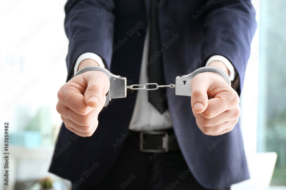 Businessman in handcuffs on blurred background Businessman in handcuffs on blurred background