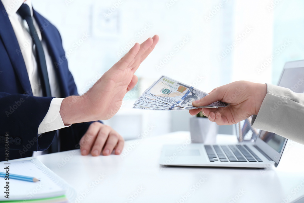 Businessman refusing to take bribe from woman at table indoors Businessman refusing to take bribe from woman at table indoors