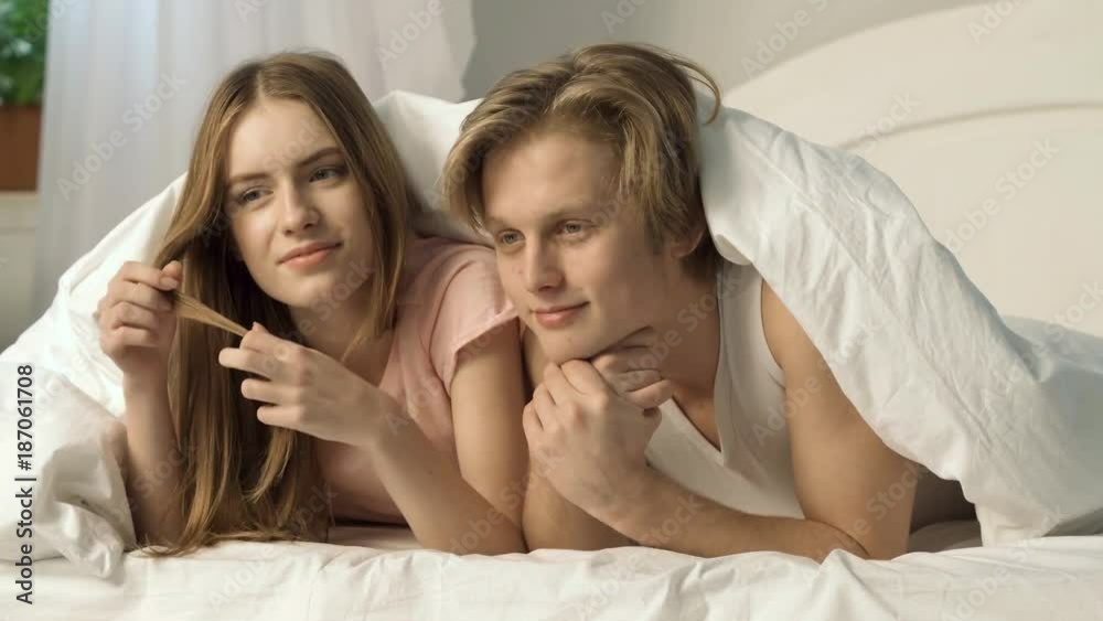 Dating loving pair is relaxing in bed. A girl softly touches her hair and her boy dreams with closed eyes. Dating loving pair is relaxing in bed. A girl softly touches her hair and her boy dreams with closed eyes.
