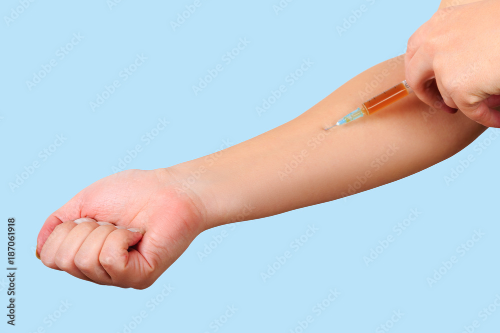 Close-up of hand, giving vaccination to patient using a syringe with brown drugs.  Sterile injection in the upper arm.