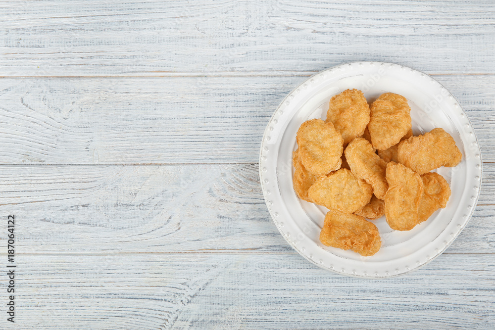 Plate with tasty chicken nuggets on table