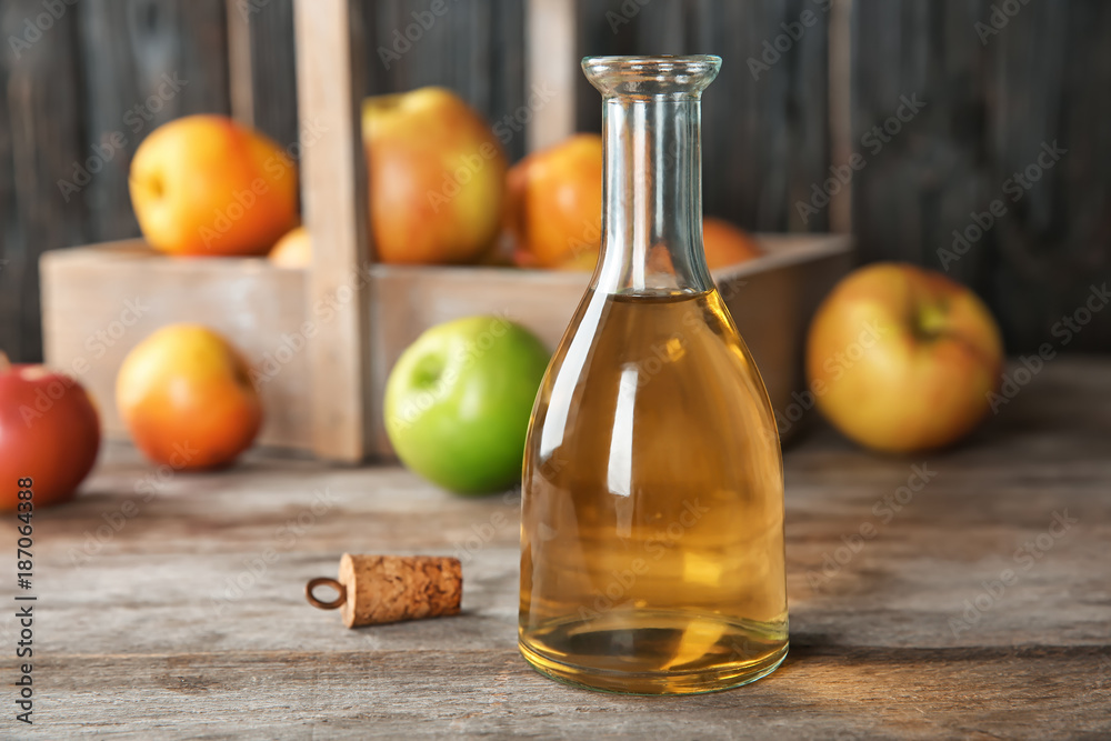 Glass bottle with apple vinegar and fresh fruit on wooden table Glass bottle with apple vinegar and fresh fruit on wooden table
