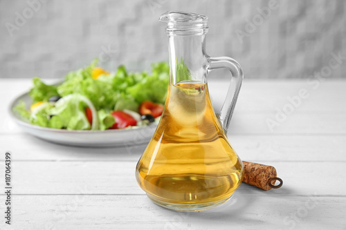 Glass jug with apple vinegar on table