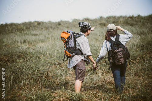 Couple of backpacking hikers going to mountain top and navigating by map paper. Backpackers or Hikers travel concept. Selective focus.