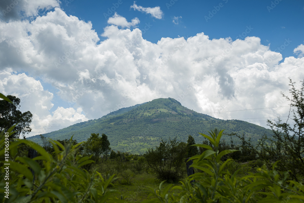 Obraz premium Summer landscape with mountains, cloudy sky, green grass and trees in Guatemala.
