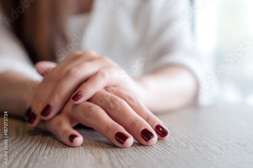 Closeup image of a woman s hands with red nails color on wooden table