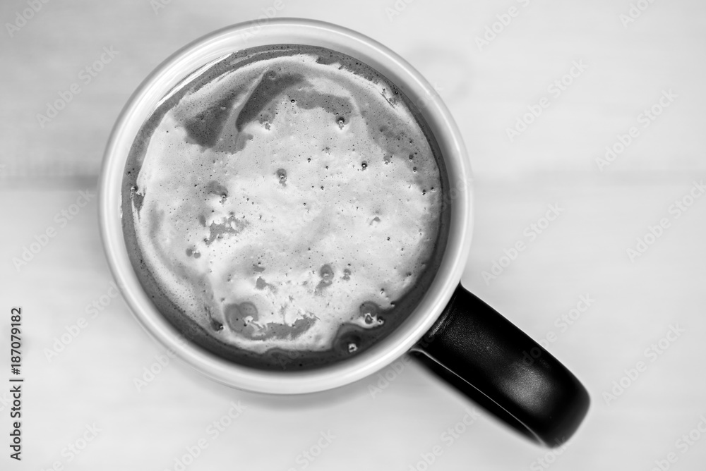 Coffee in a black mug on a yellow wooden background Coffee in a black mug on a yellow wooden background