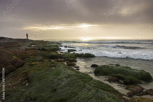 Distant Isolated Person enjoying Dramatic Sunset Sky over Pacific Ocean at Windansea Beach south of La Jolla California
