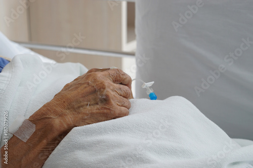 Hand of sick elderly patient lying on the bed in hospital