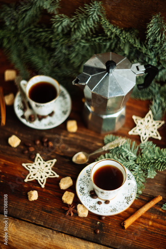 Two cups of espresso with pieces of cane sugar and Italian coffee maker on wooden table.