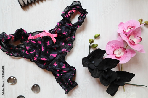 Black and pink string panties with flowers on a white background. Women's Accessories with Black and Rose Orchid