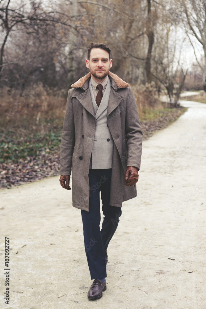 Handsome elegant man in the park wear suit and coat. Handsome elegant man in the park wear suit and coat.
